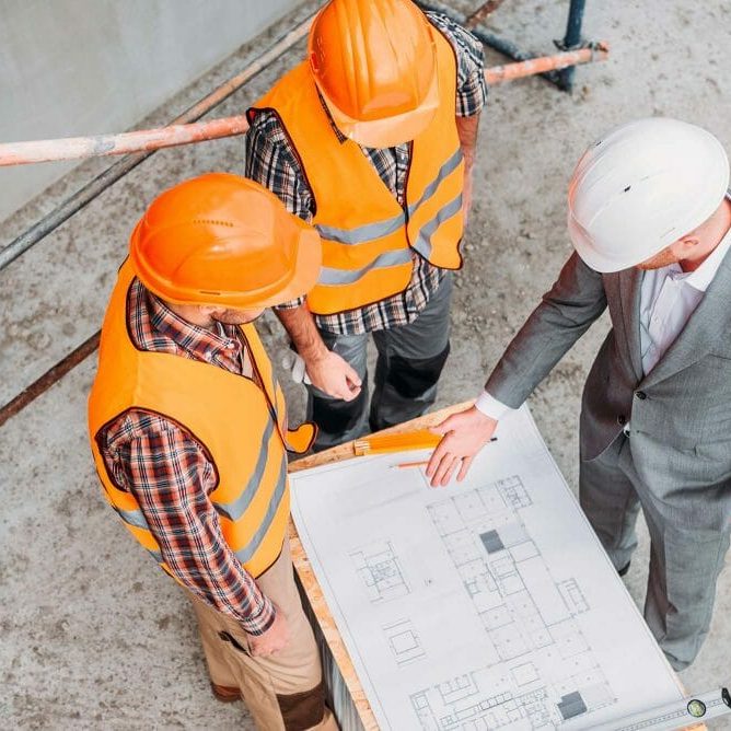 Men in hard hats looking at building plans